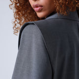 Lady wearing a gray blazer with a plain background
