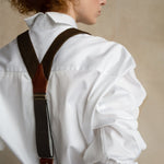 Woman in white business shirts with wool suspenders, back view