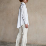 Woman in white shirt standing full length confidently, looking forward, side view