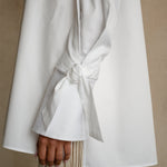 Adjustable ribbon cuff on a white gabardine shirt with extended sleeve and refined structured drape, detail view