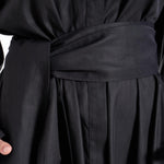 Close-up of the matching fabric belt and front fastening detail on the black shirt dress worn by a model