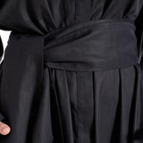 Close-up of the matching fabric belt and front fastening detail on the black shirt dress worn by a model