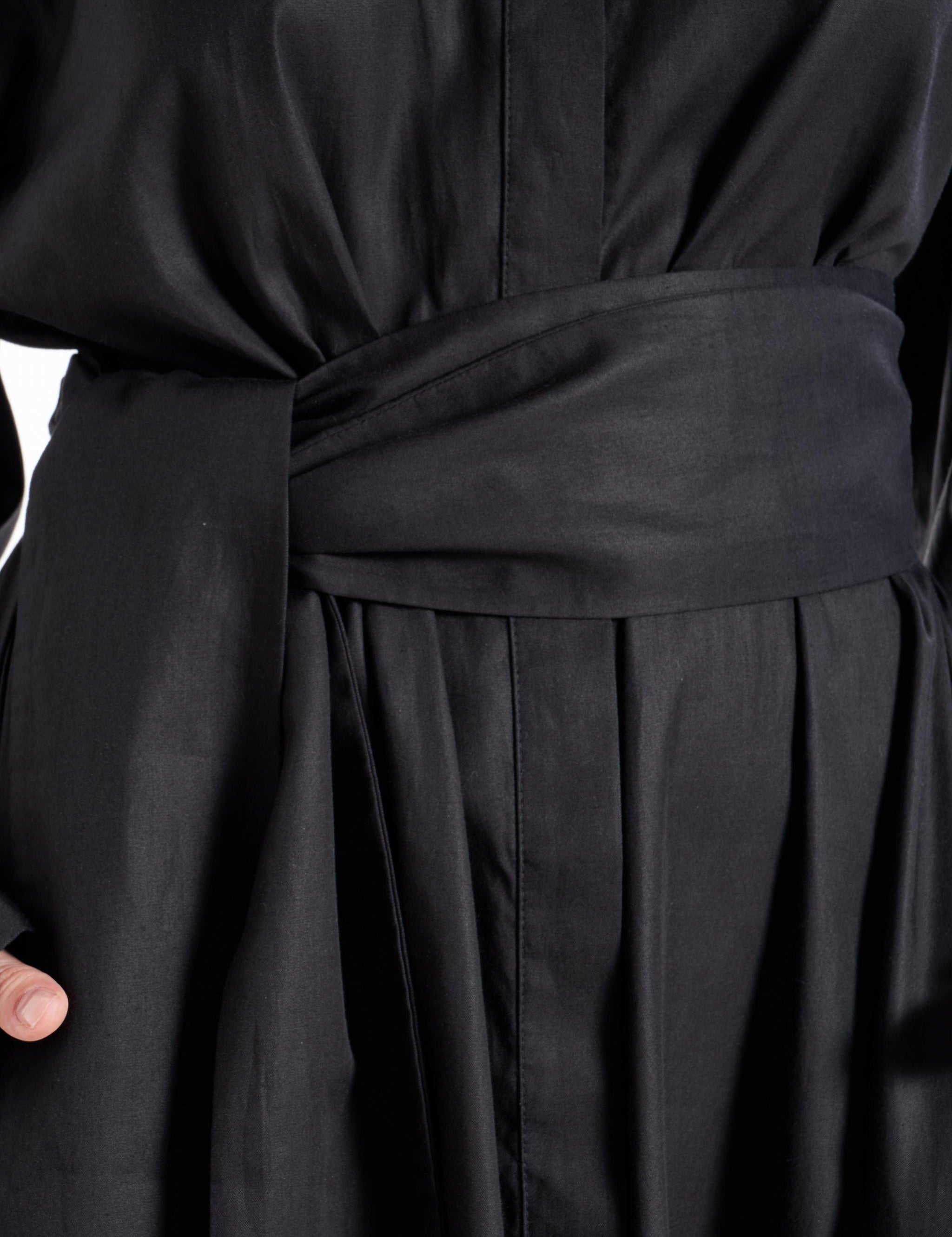 Close-up of the matching fabric belt and front fastening detail on the black shirt dress worn by a model