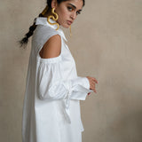 Cold-shoulder white cotton gabardine shirt with voluminous puff sleeves and ribbon cuffs, worn by a model