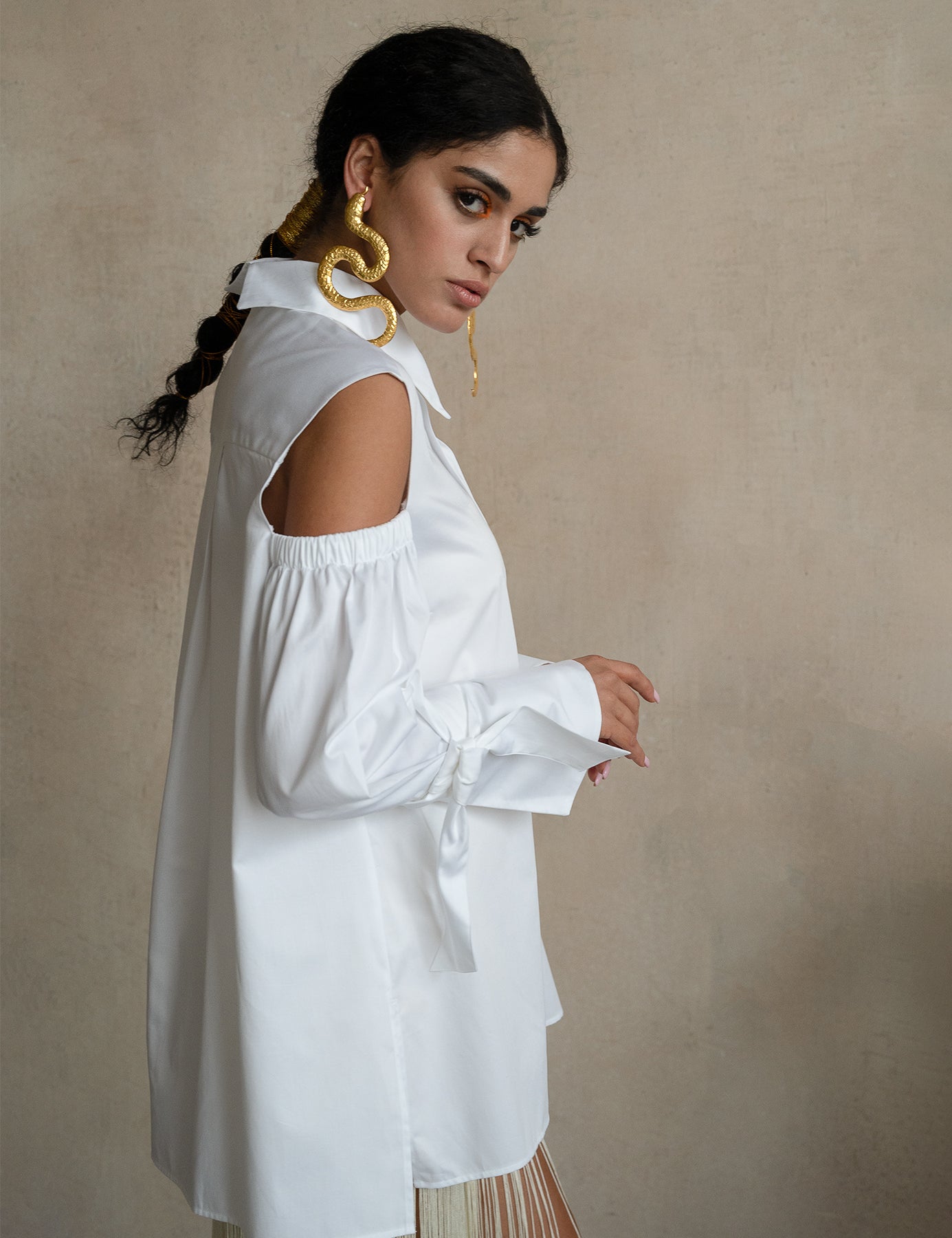 Cold-shoulder white cotton gabardine shirt with voluminous puff sleeves and ribbon cuffs, worn by a model