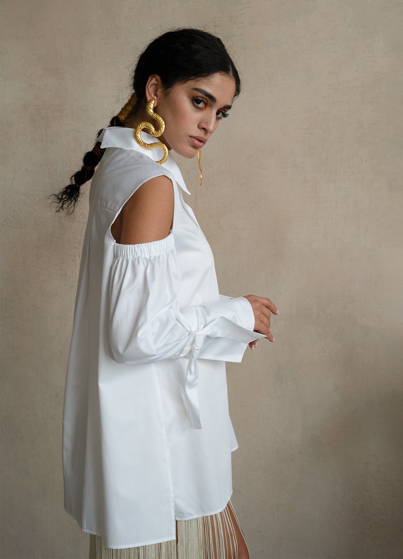 Cold-shoulder white cotton gabardine shirt with voluminous puff sleeves and ribbon cuffs, worn by a model
