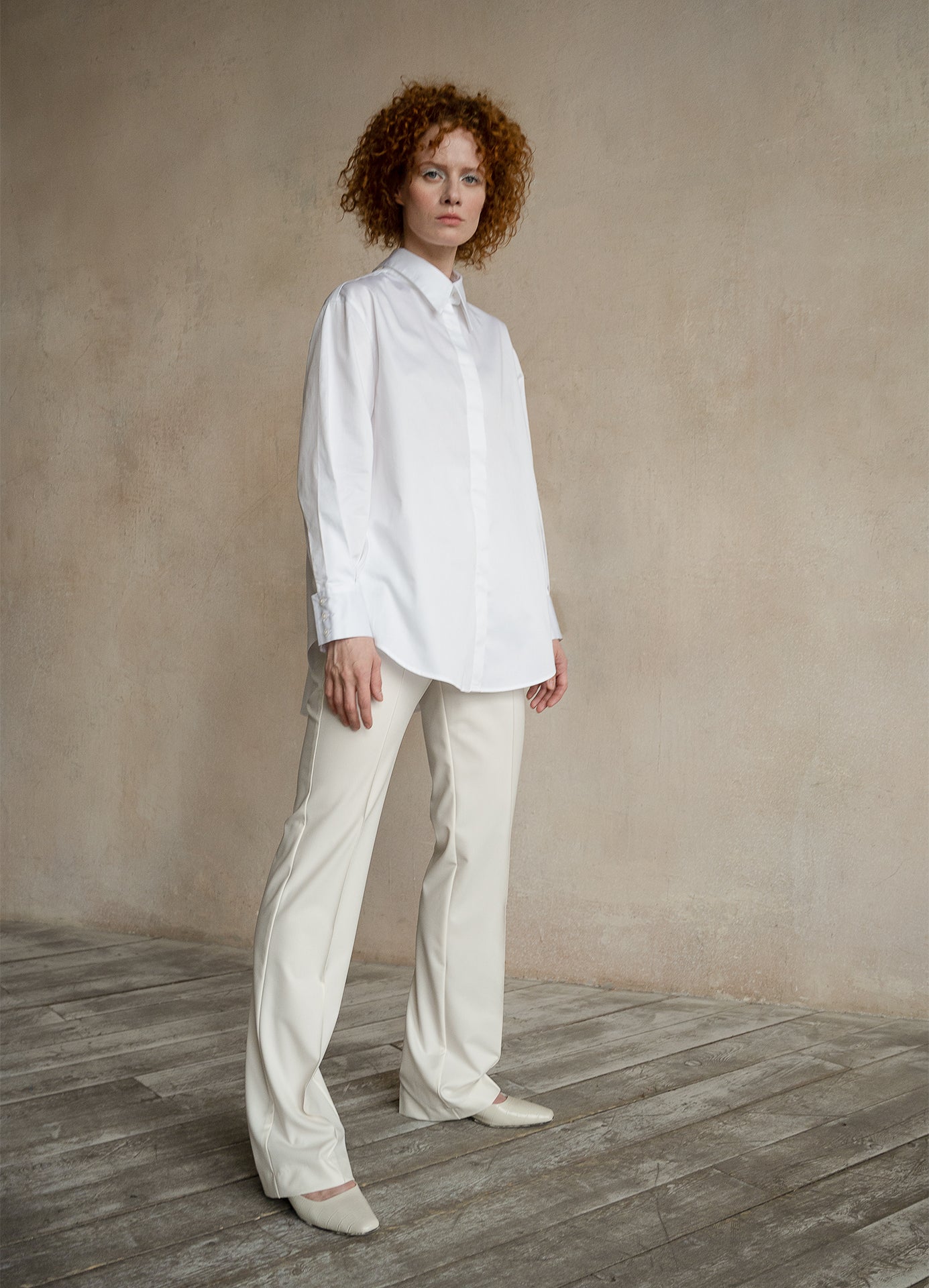 Relaxed-fit button-down shirt worn by a model with a curved hem and contemporary tailoring