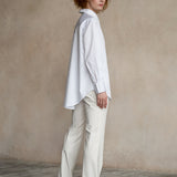 Side view of a model wearing an elegant white cotton work shirt with a relaxed silhouette