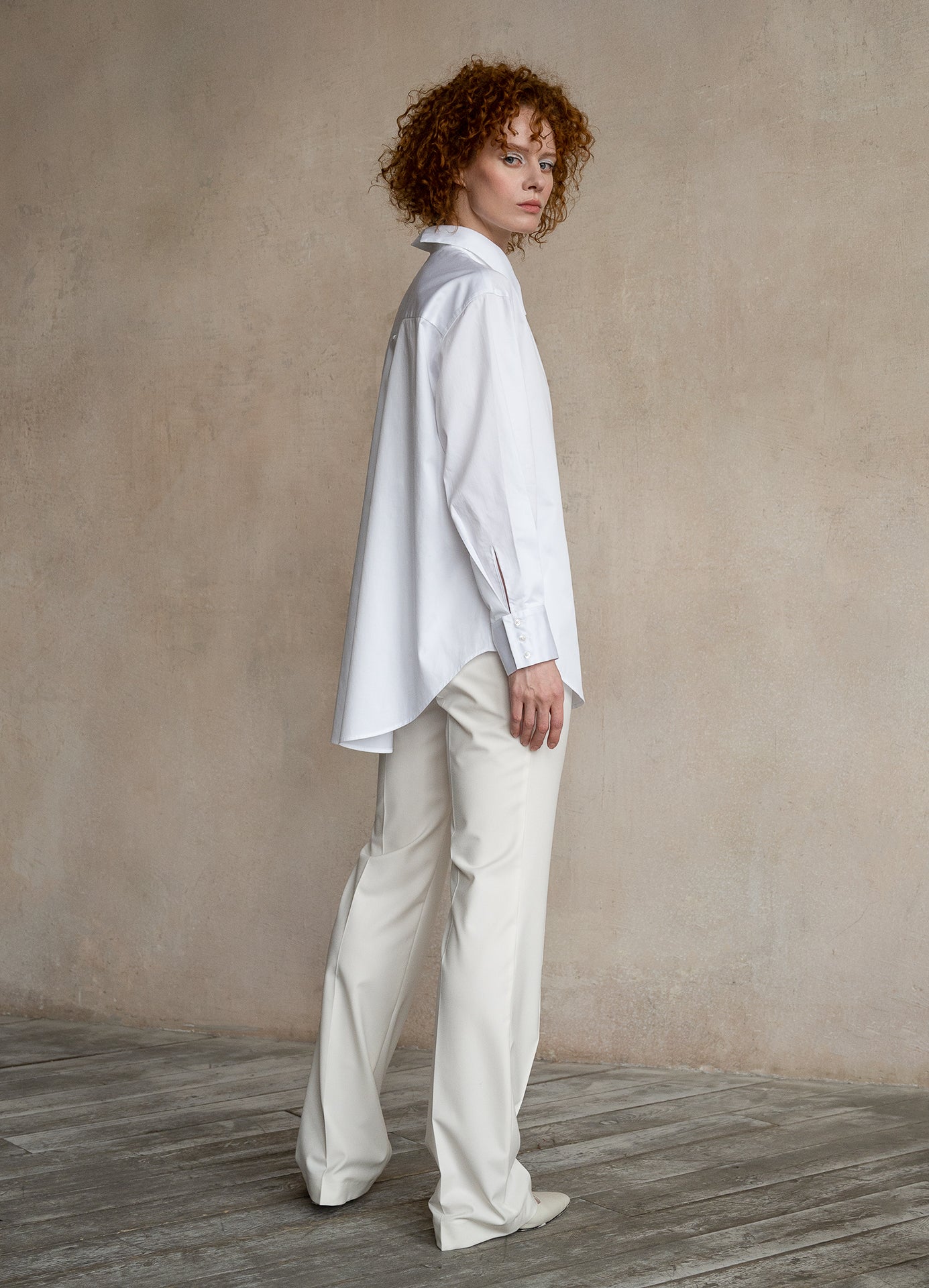 Side view of a model wearing an elegant white cotton work shirt with a relaxed silhouette