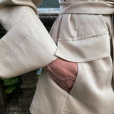 Belted linen blazer with deep flap pocket and wide turn-back cuff, close-up on a model at Lake Como
