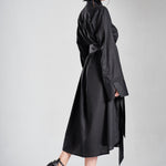 Luxury black long shirt dress worn by a model in a full-length side pose with an elegant flowing silhouette
