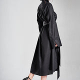 Luxury black long shirt dress worn by a model in a full-length side pose with an elegant flowing silhouette