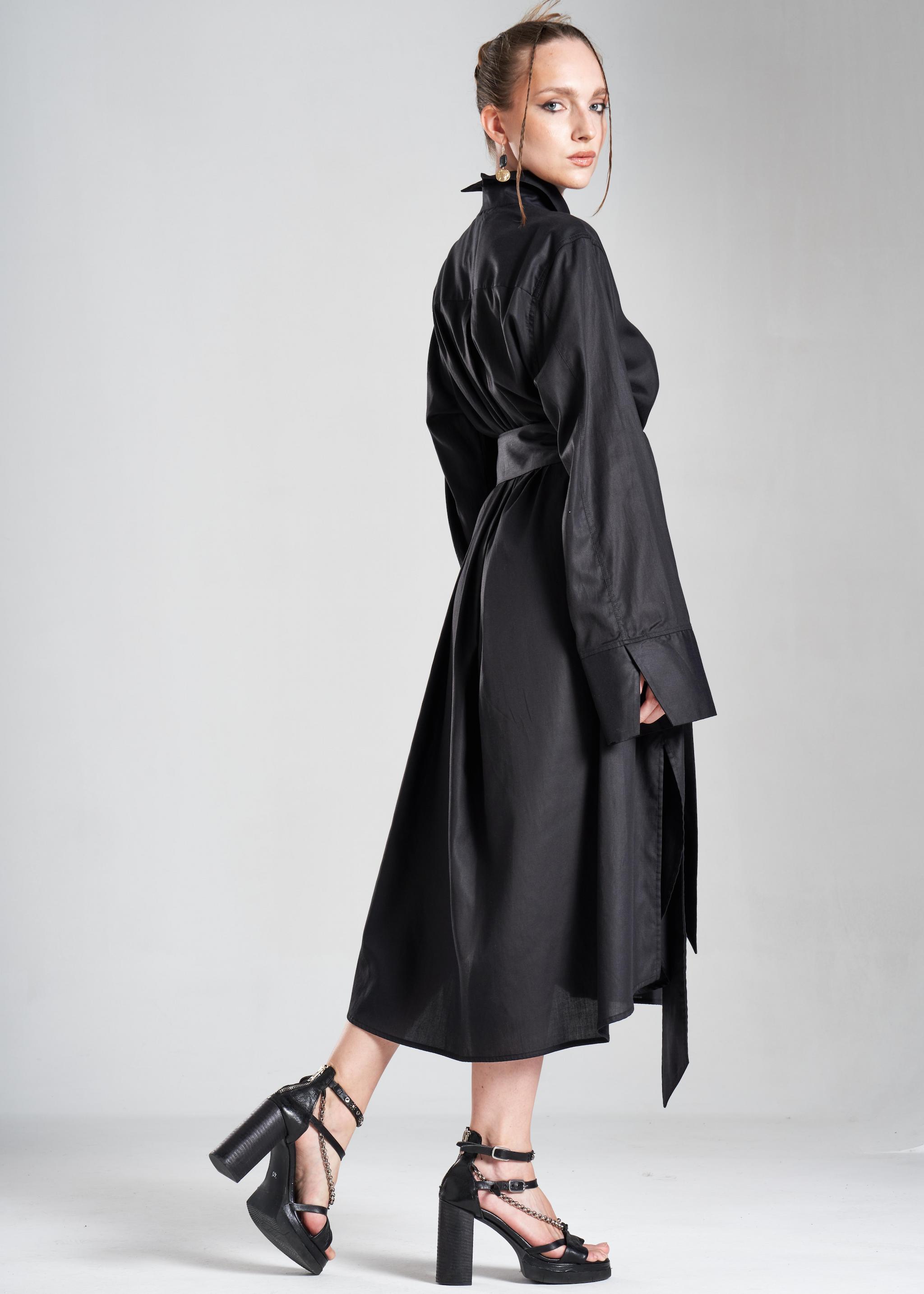 Luxury black long shirt dress worn by a model in a full-length side pose with an elegant flowing silhouette