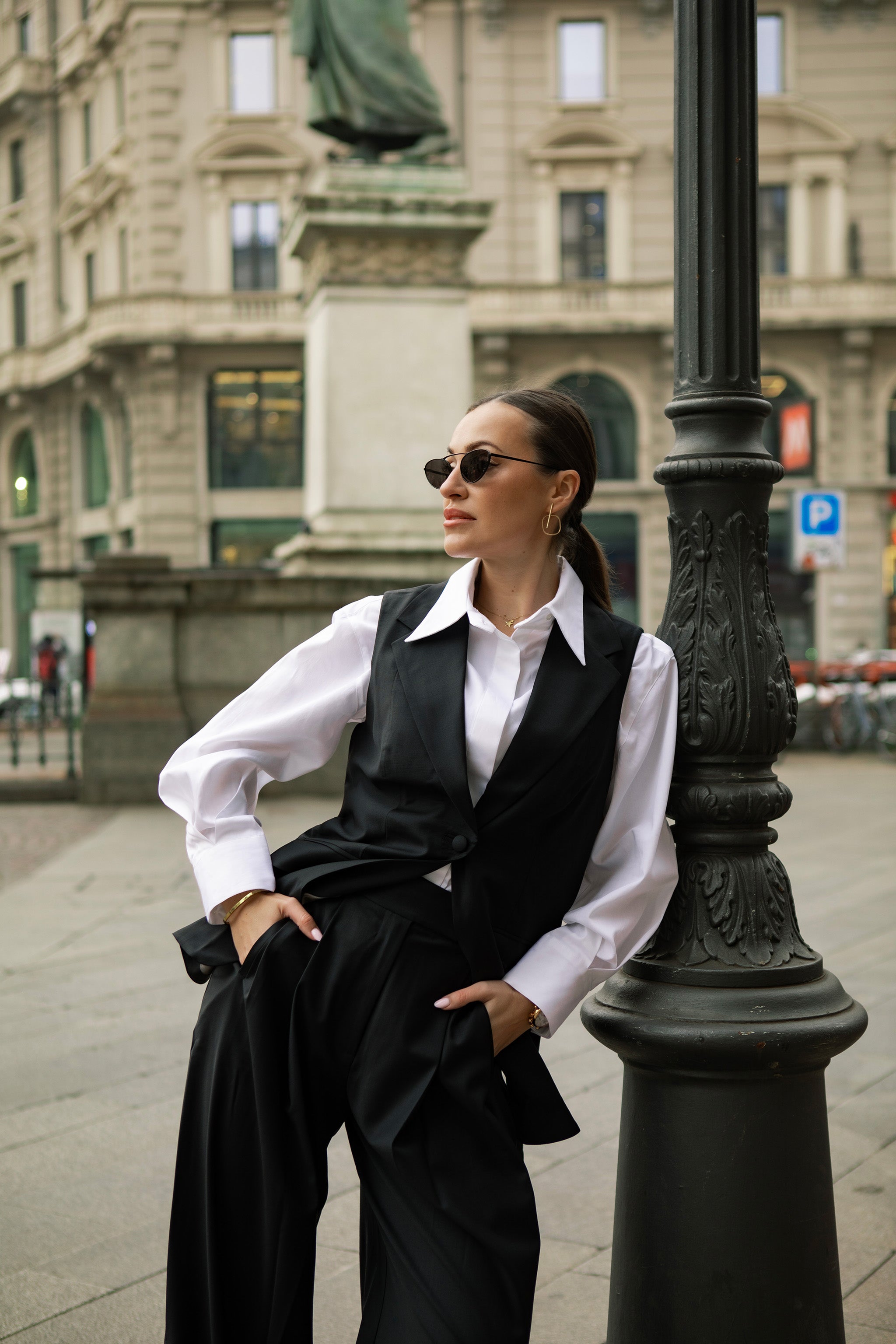 Model in Milan wearing a premium white cotton shirt under a tailored black waistcoat with wide-leg suit pants for an office look