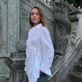 Luxury Italian white cotton draped wrap shirt worn by a model with a fluid asymmetric silhouette