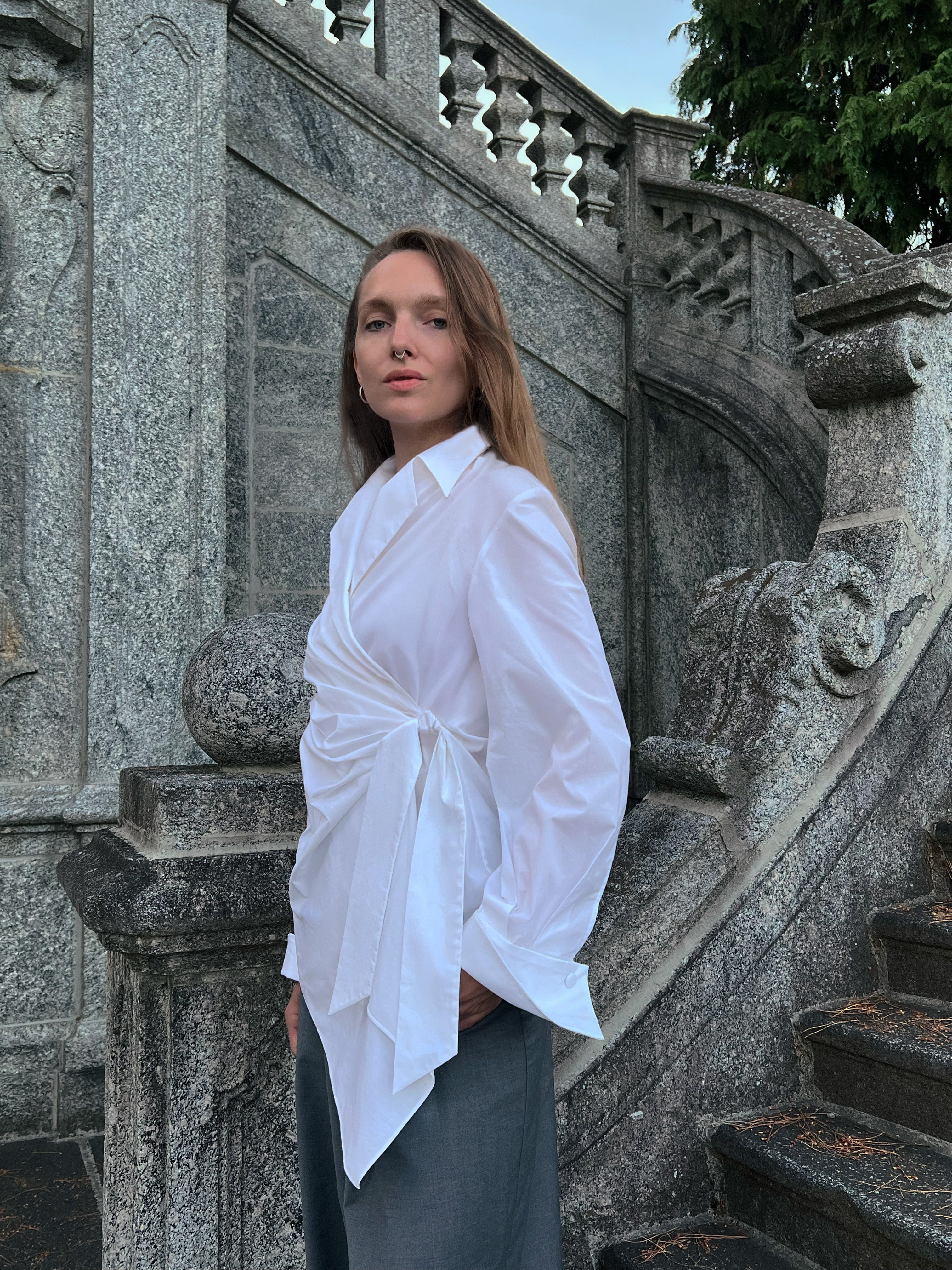 Luxury Italian white cotton draped wrap shirt worn by a model with a fluid asymmetric silhouette