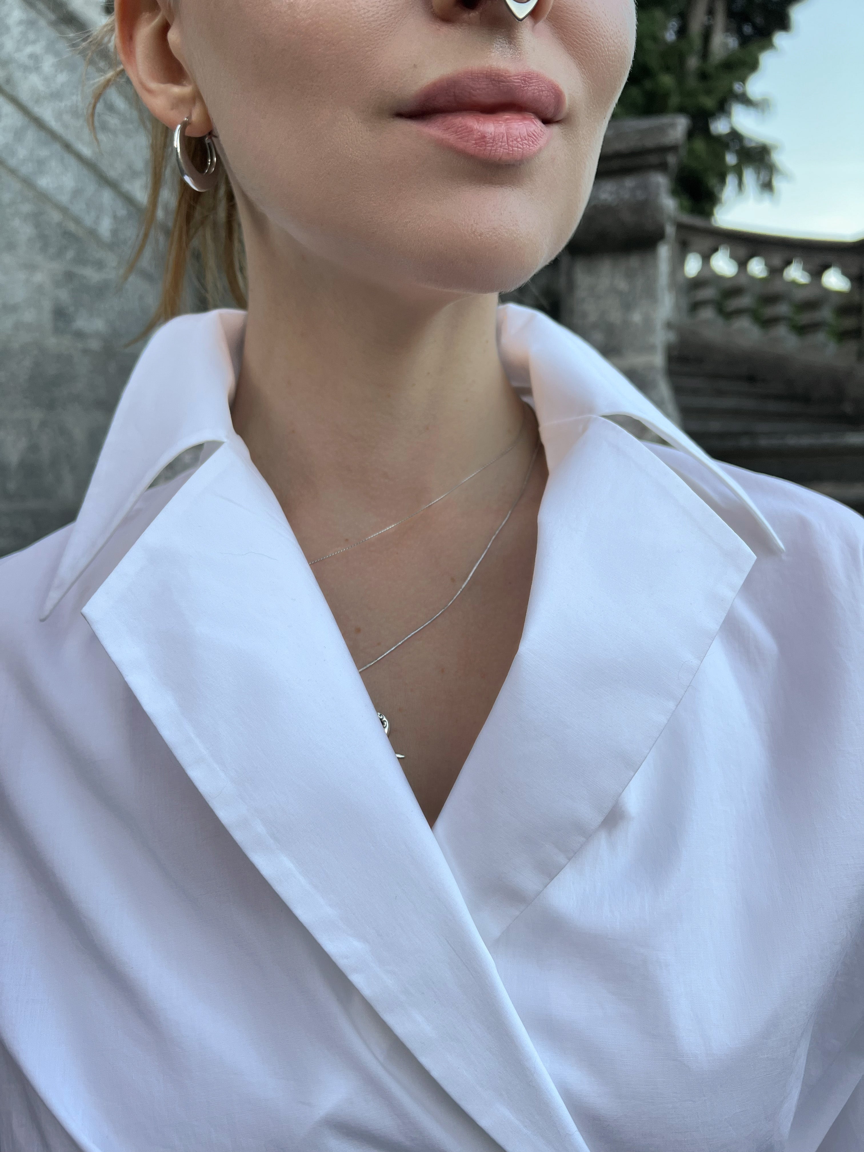 Close-up of a luxury Italian white cotton shirt worn by a model, highlighting the elegant notched lapel
