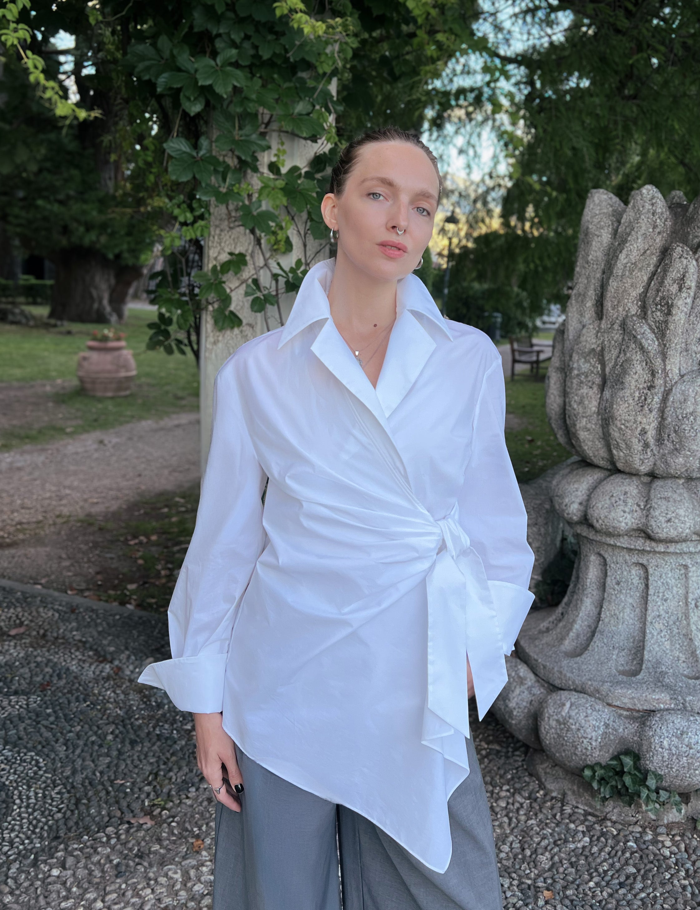 Luxury white asymmetric lapel collar shirt worn by a model, featuring an elegant wrap front and fluid drape