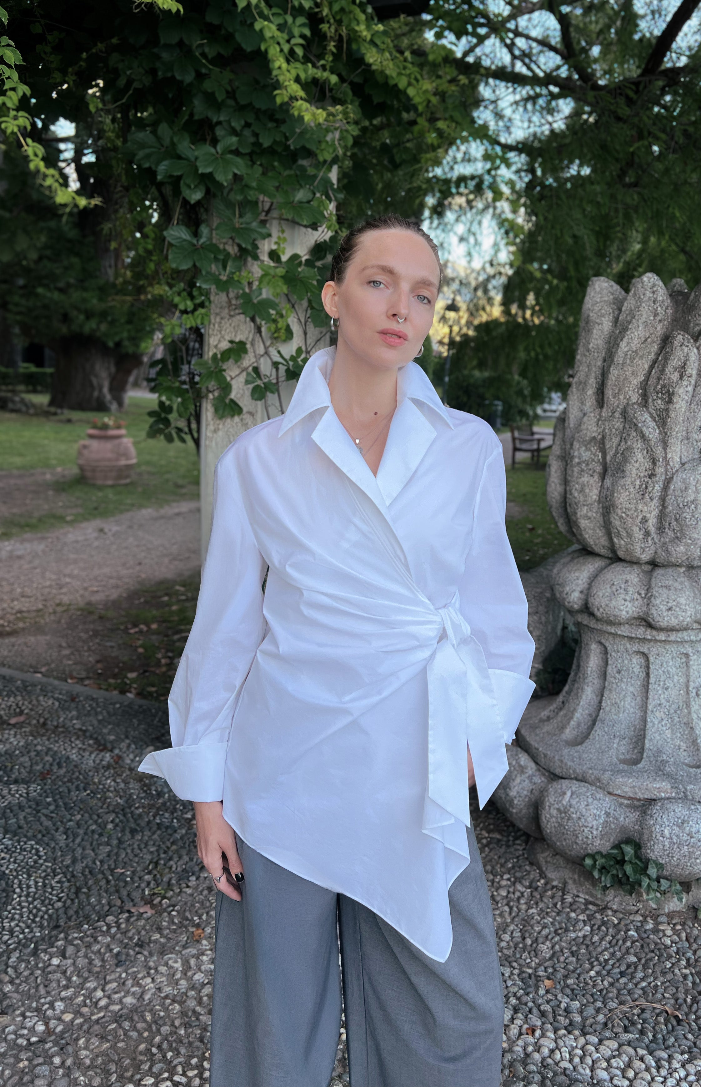 Luxury white asymmetric lapel collar shirt worn by a model, featuring an elegant wrap front and fluid drape