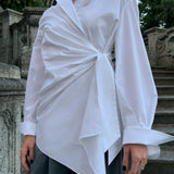 Luxury white cotton asymmetric wrap shirt worn by a model, highlighting the elegant draped front