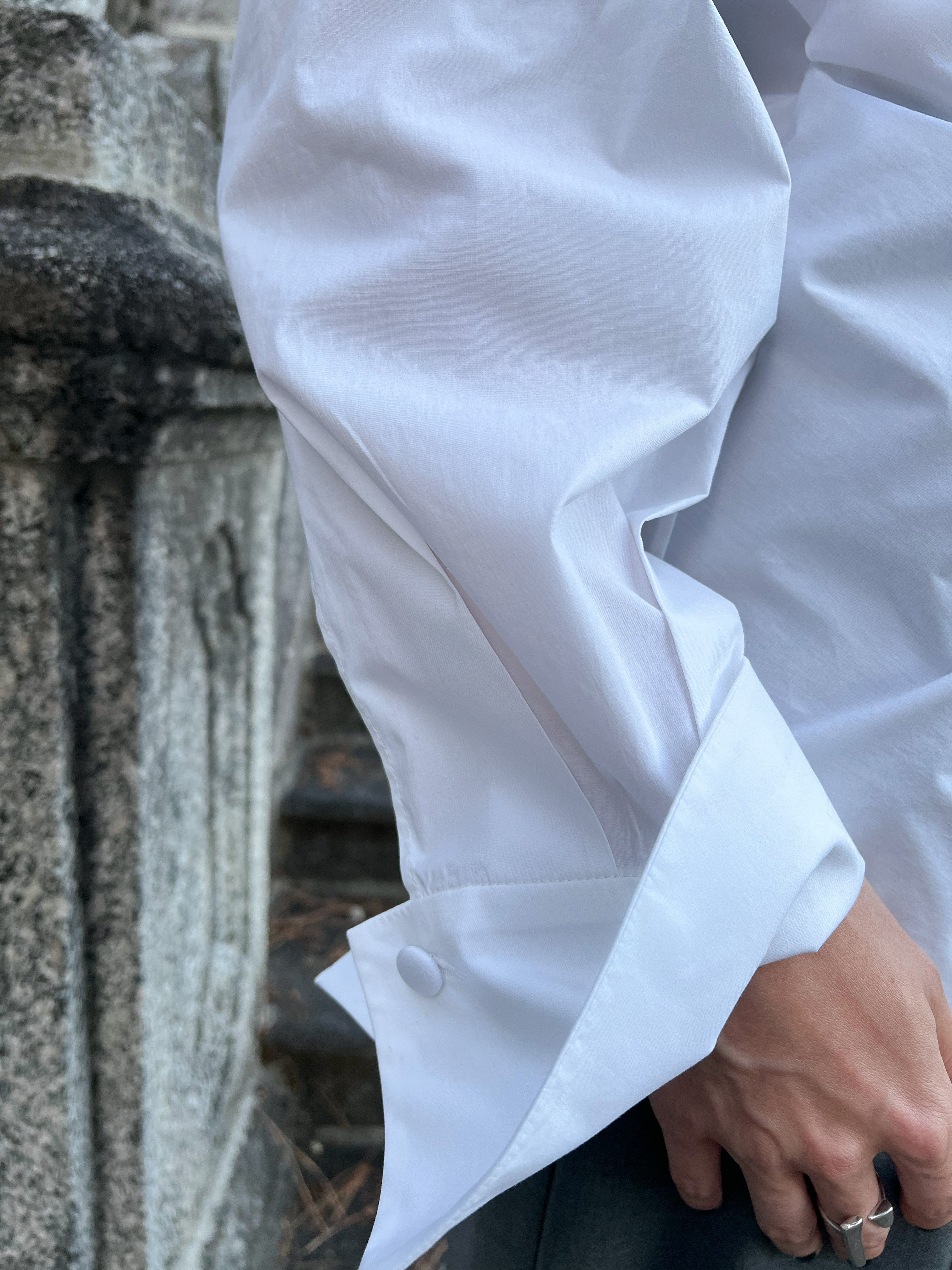 Close-up of a luxury white cotton three-button petal cuff on a shirt worn by a model
