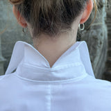 Close-up of a luxury white cotton shirt worn by a model, revealing the signature split-back collar