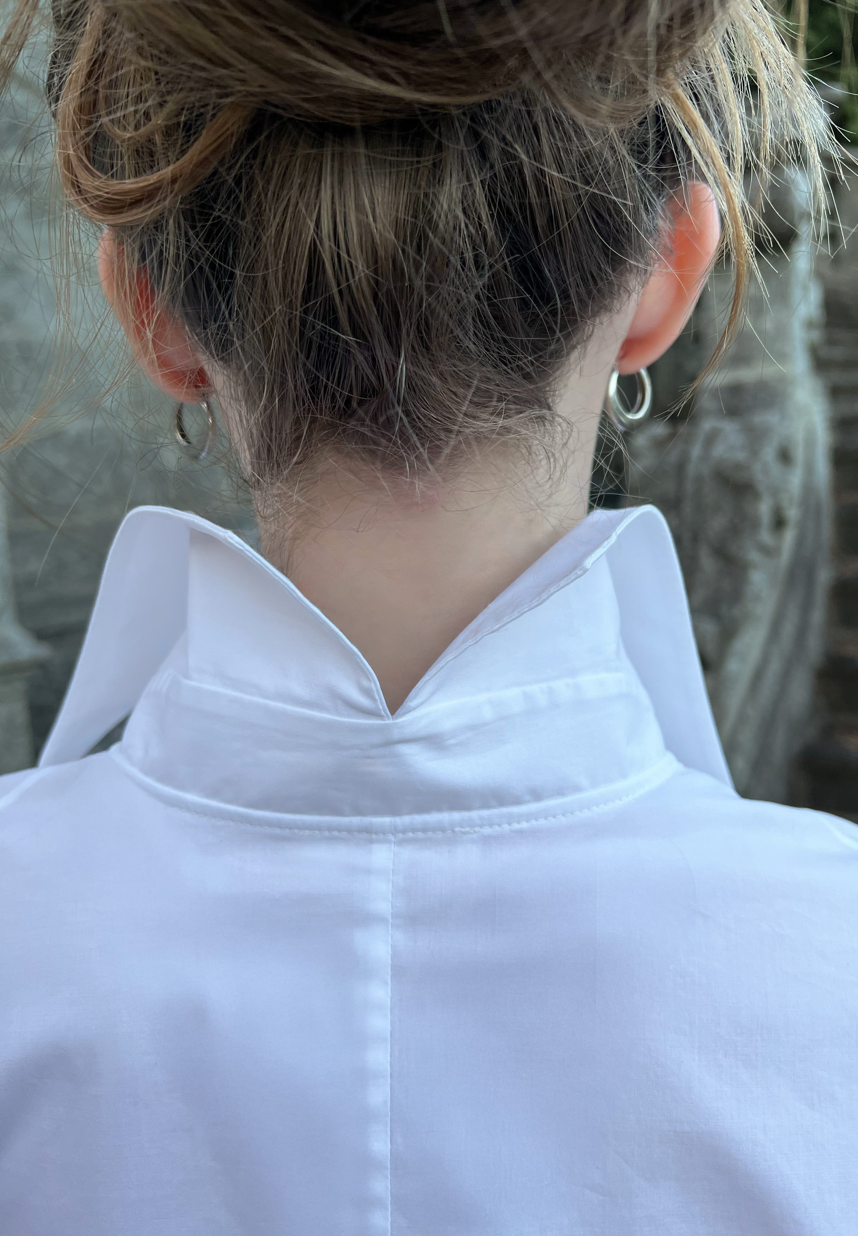 Close-up of a luxury white cotton shirt worn by a model, revealing the signature split-back collar