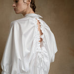 Luxury white open-back shirt worn by a model from the back, showing puff sleeves and drawstring detail