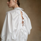 Luxury white open-back shirt worn by a model from the back, showing puff sleeves and drawstring detail