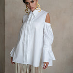 Off-shoulder Italian white cotton shirt with puff sleeves, extended cuffs and a fluid elongated silhouette on a model