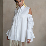 Off-shoulder Italian white cotton shirt with puff sleeves, extended cuffs and a fluid elongated silhouette on a model