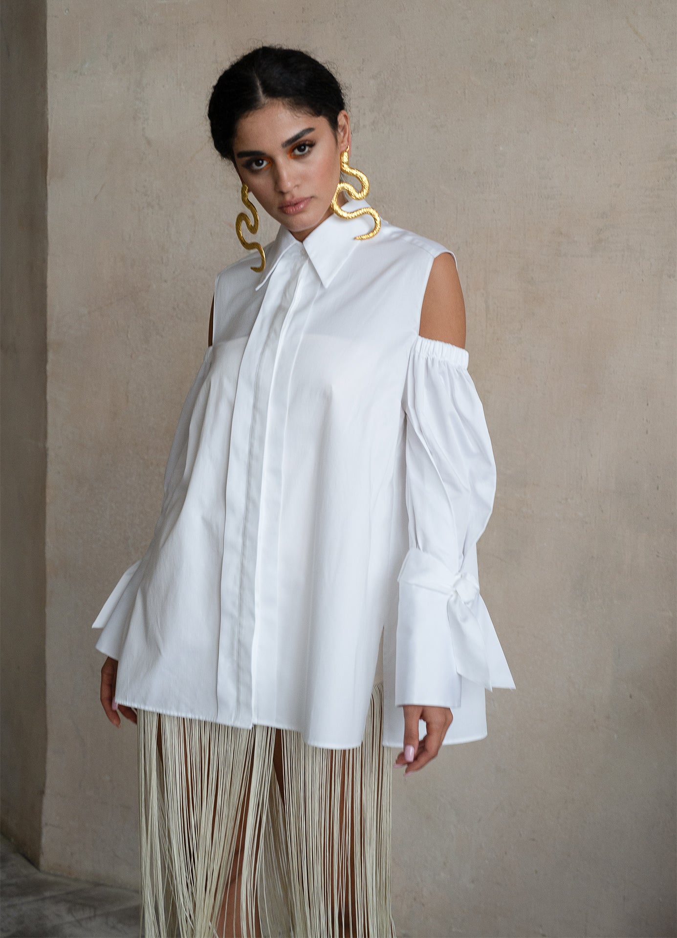Off-shoulder Italian white cotton shirt with puff sleeves, extended cuffs and a fluid elongated silhouette on a model