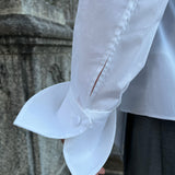 Close-up of a premium Italian white cotton shirt worn by a model, highlighting the elegant petal cuff