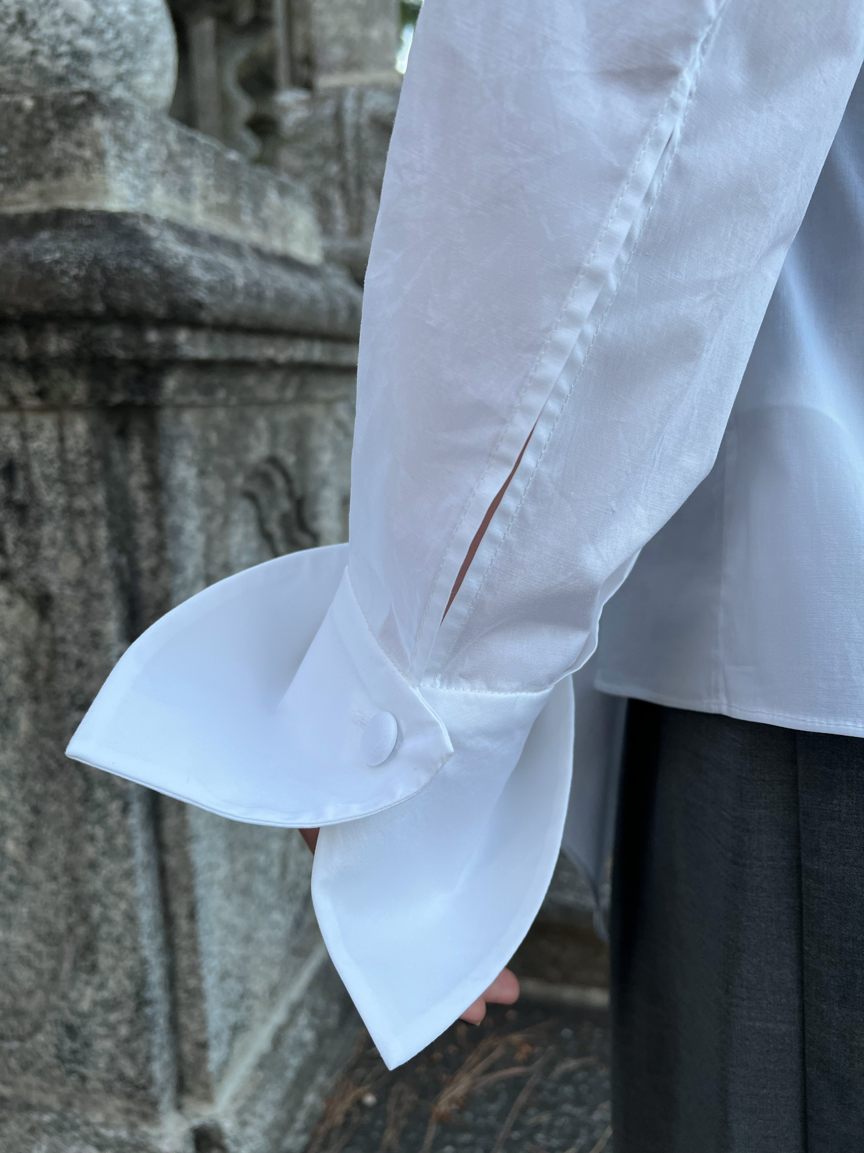 Close-up of a premium Italian white cotton shirt worn by a model, highlighting the elegant petal cuff