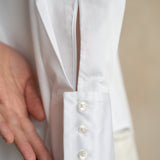 Close-up of the three-button cuff on a professional white cotton office shirt worn by a model