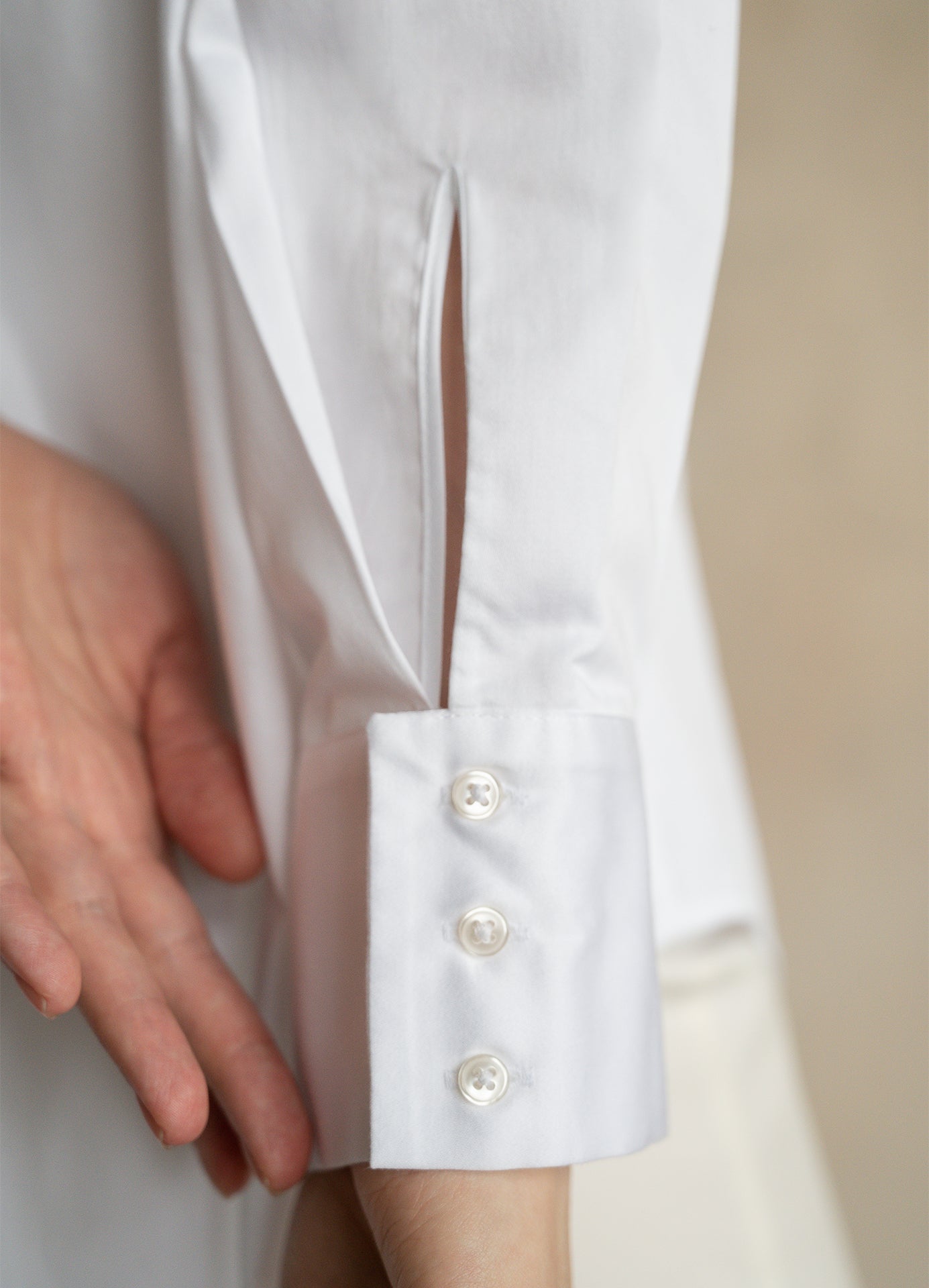 Close-up of the three-button cuff on a professional white cotton office shirt worn by a model