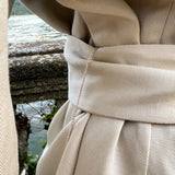 Close-up of a model wearing a luxury belted linen blazer with a self-tie waist belt, refined twill weave and Lake Como