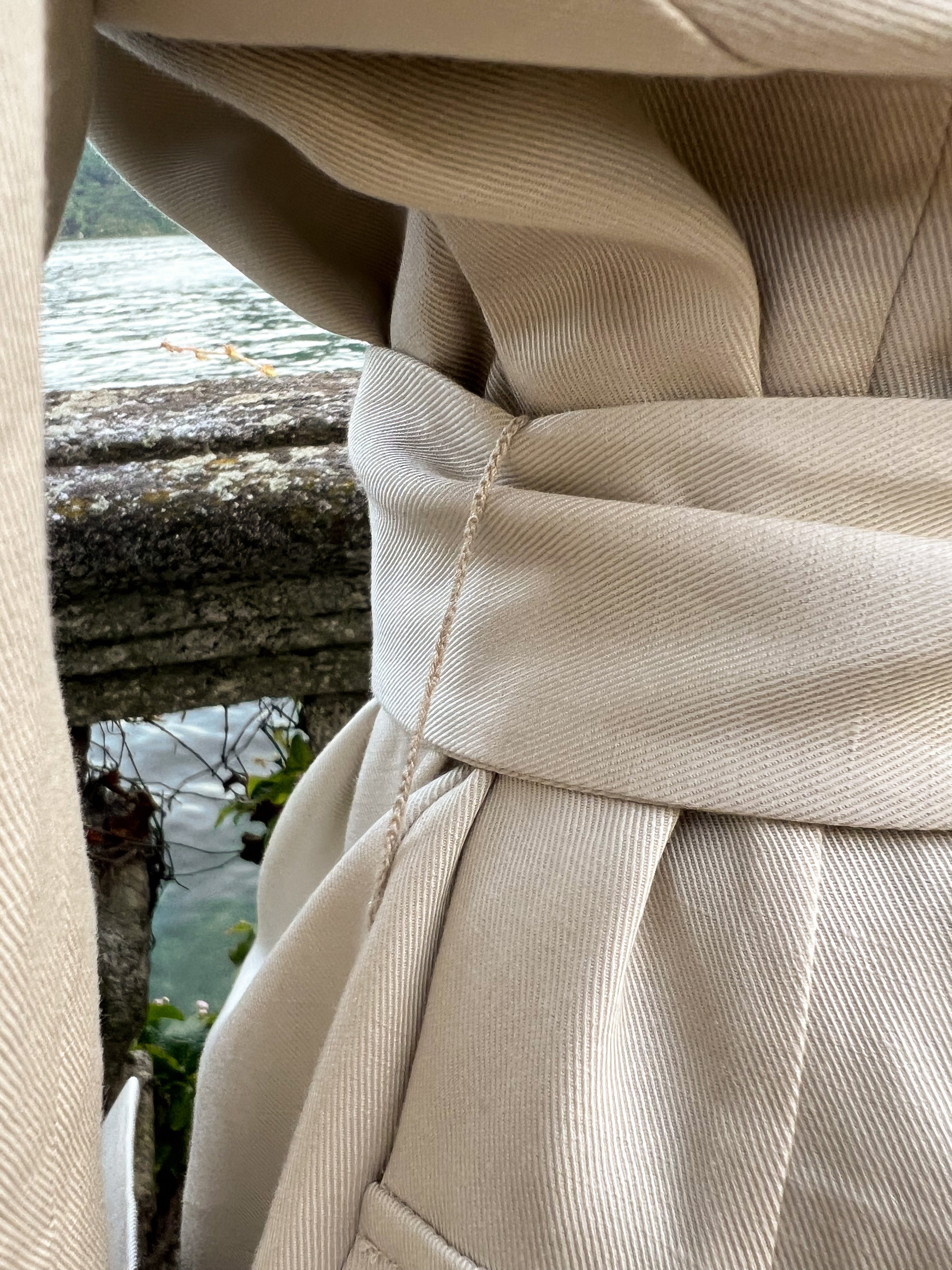 Close-up of a model wearing a luxury belted linen blazer with a self-tie waist belt, refined twill weave and Lake Como