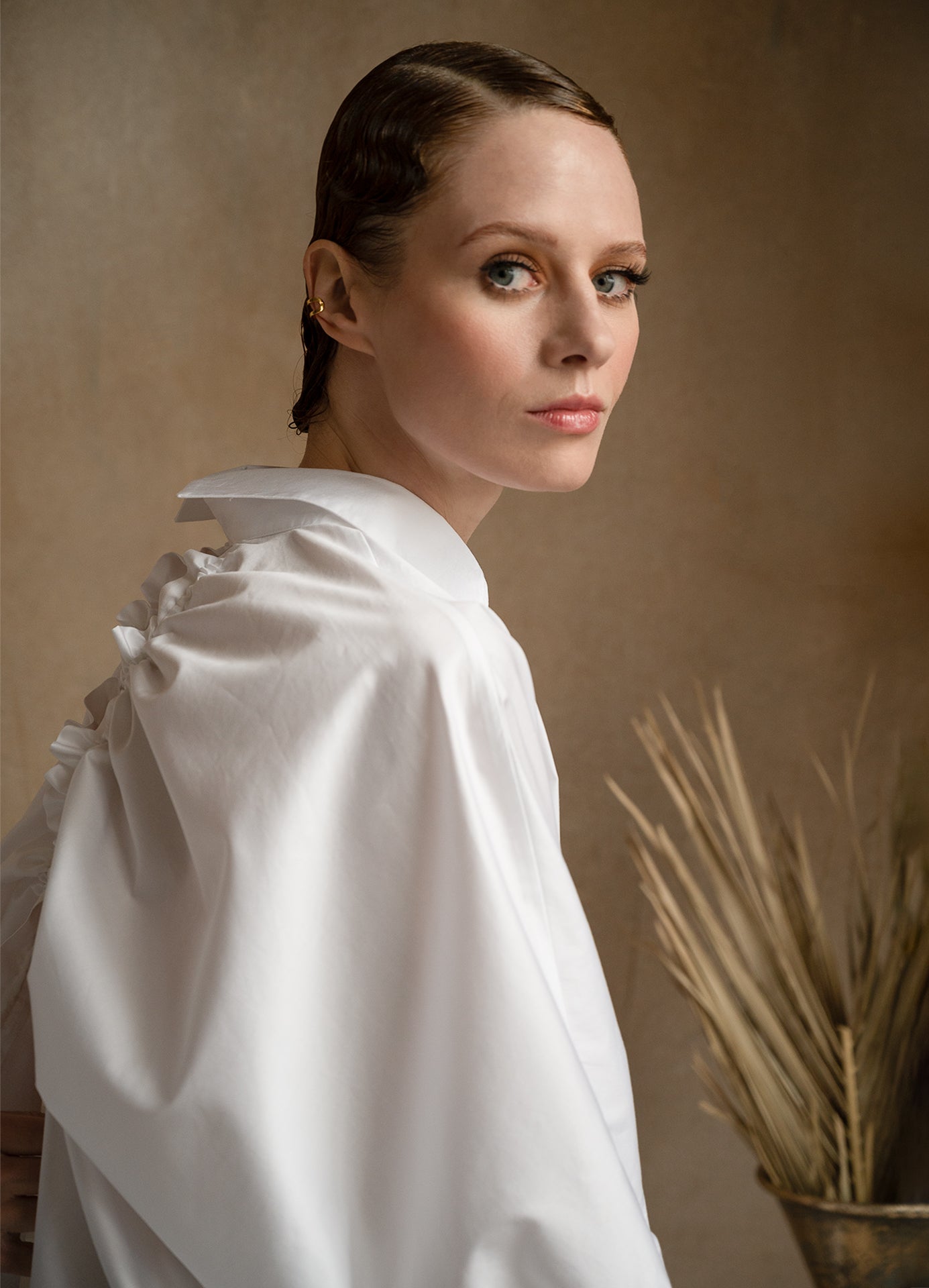 Side view of a model wearing a luxury white shirt with a signature split-back collar and elegant puff sleeves