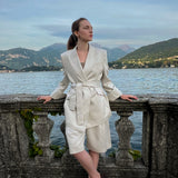Belted linen-blend blazer with peaked lapels and relaxed tailoring, worn by a model at Lake Como, Italy