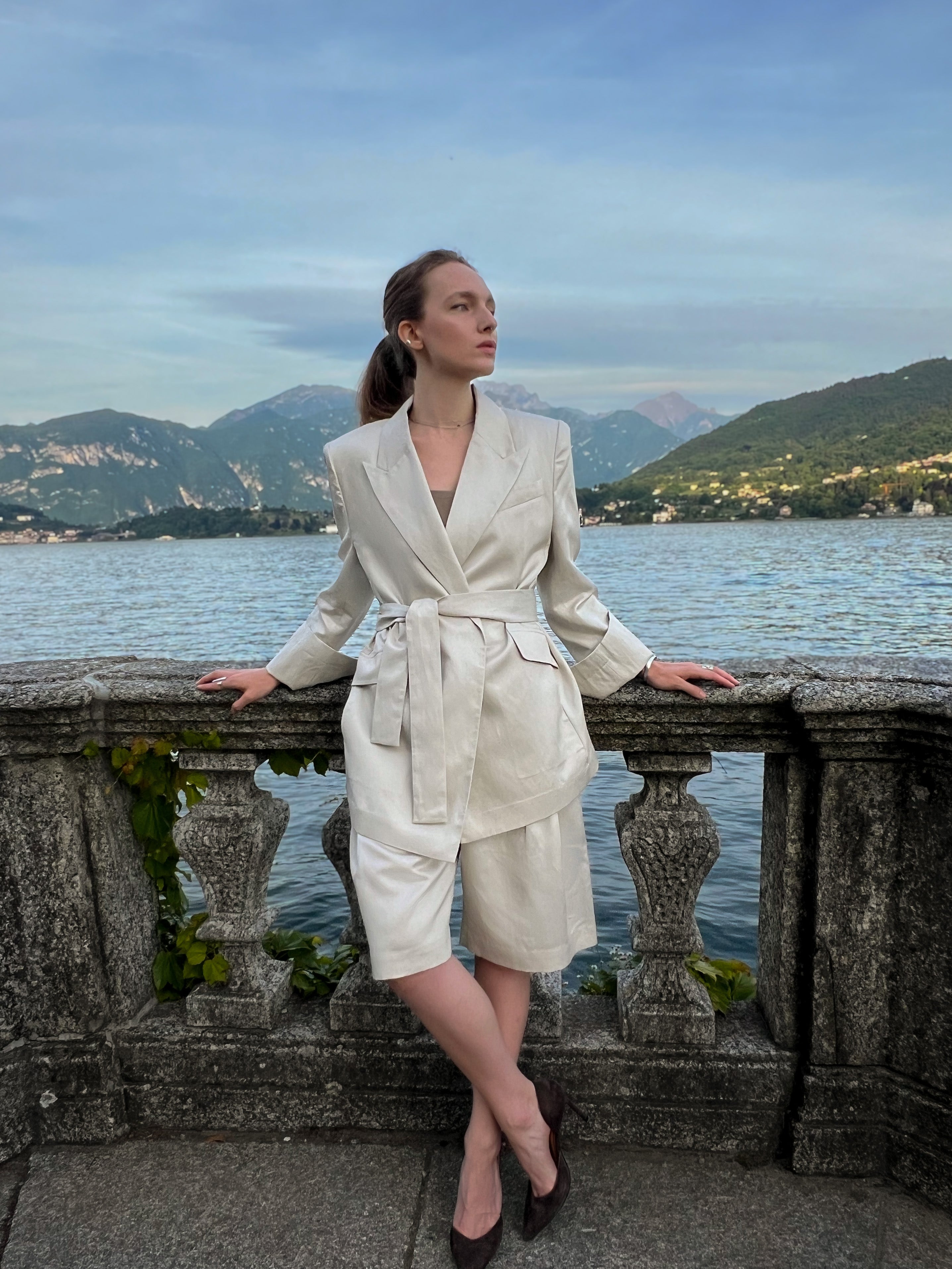 Belted linen-blend blazer with peaked lapels and relaxed tailoring, worn by a model at Lake Como, Italy
