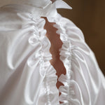 Sculptural white shirt worn by a model in a close-up back pose, showing the drawstrings and split collar