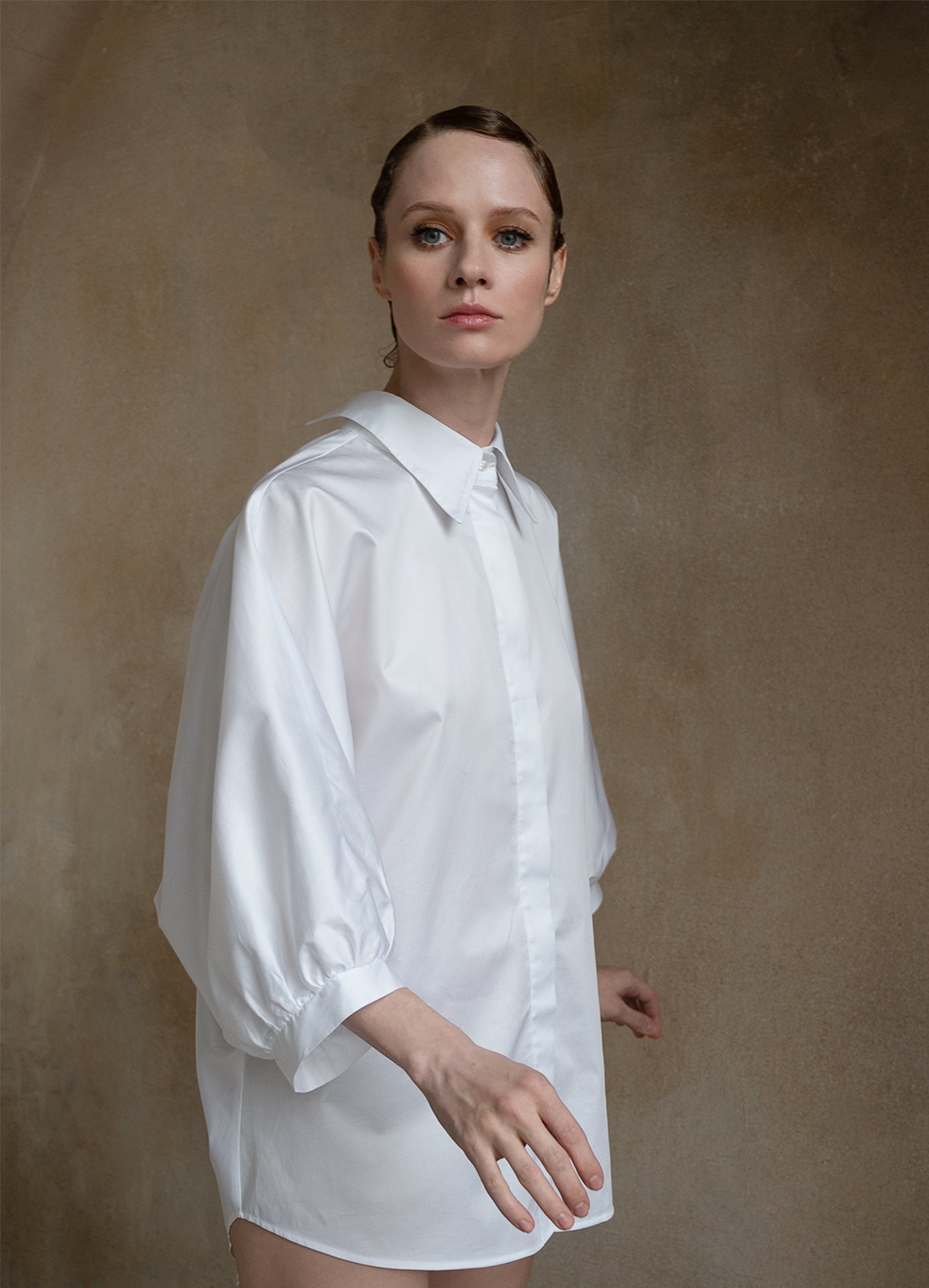 White puff-sleeve shirt worn by a model in a three-quarter front pose, showing its sculptural volume