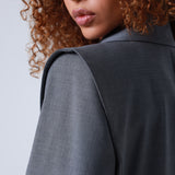 Lady wearing a gray blazer with a plain background