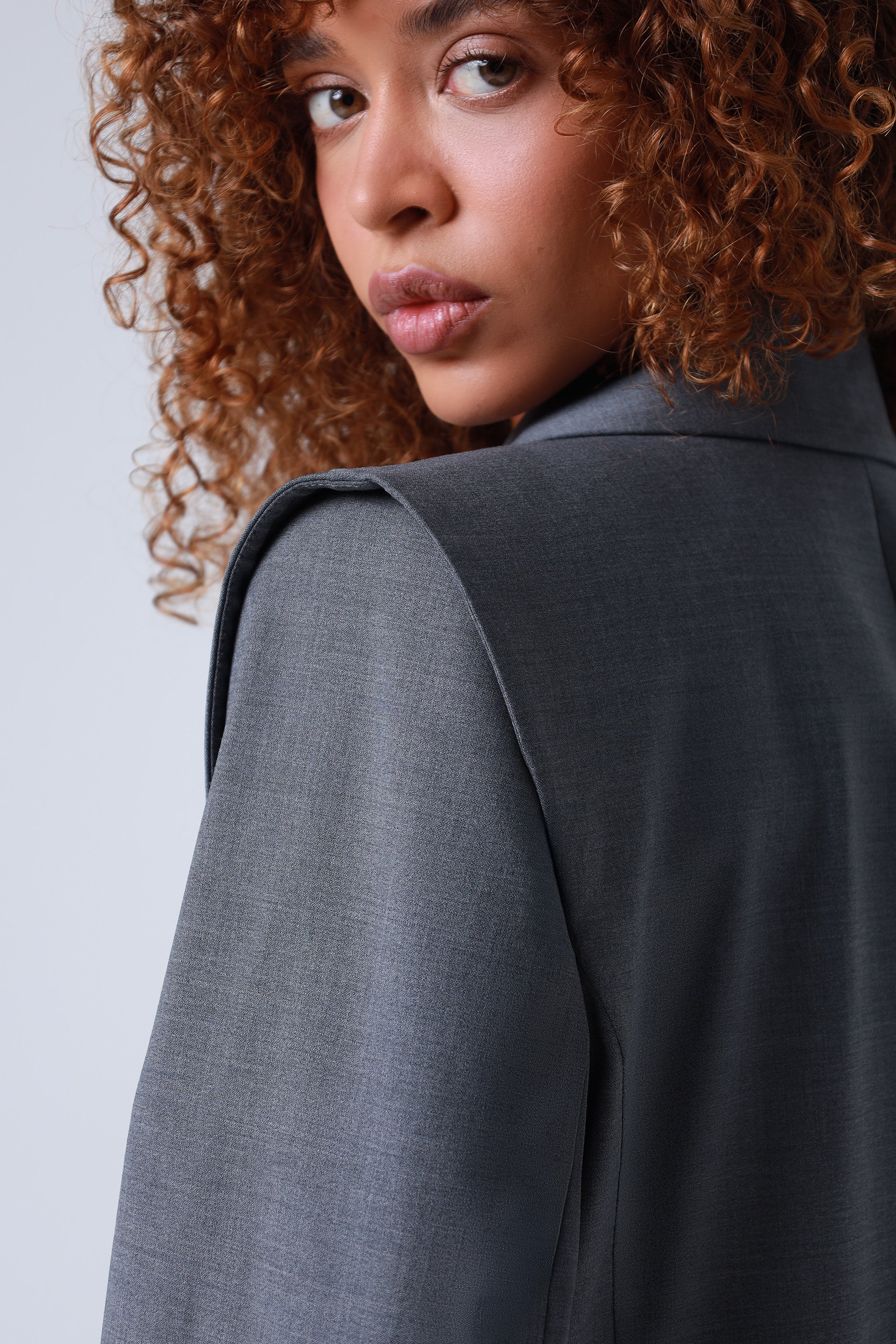 Lady wearing a gray blazer with a plain background